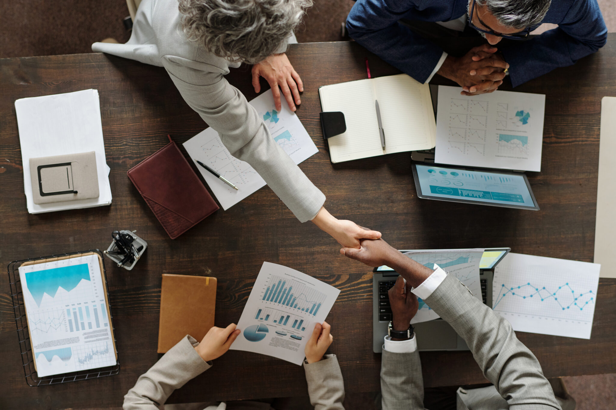 multiethnic middle aged businesspeople shaking hands during office meeting
